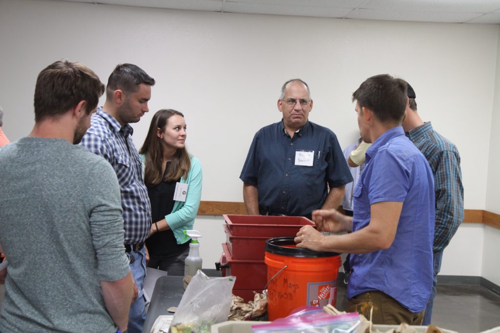 photo of 6 people standing around a bucket of compost